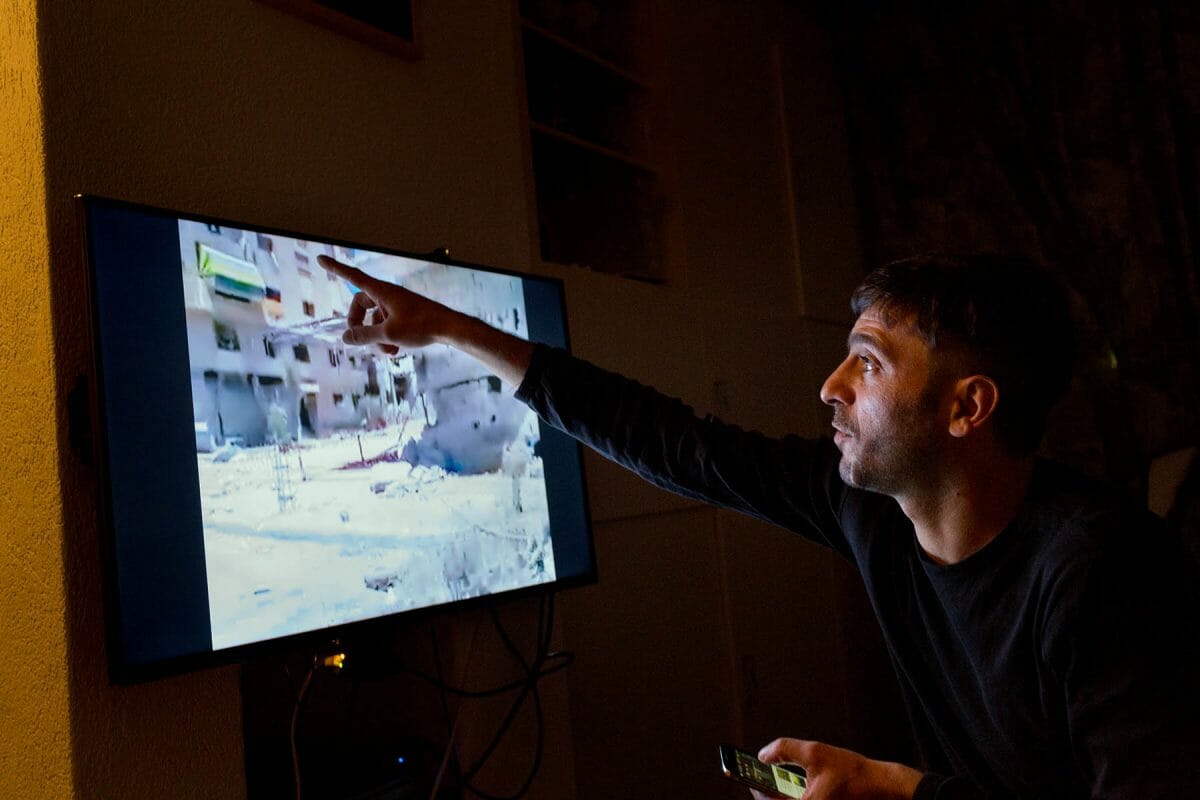 Aiman wijst op zijn tv in zijn woning in Sassenheim het huis aan waar zij ooit in Al-Tal woonde, op de beelden is het verwoeste gebied te zien, 4 november 2016.